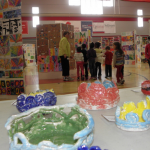 Pottery created by Glover third-graders in the foreground, as Tucker students tour the Copeland Field house, which was full of art from grades K-12